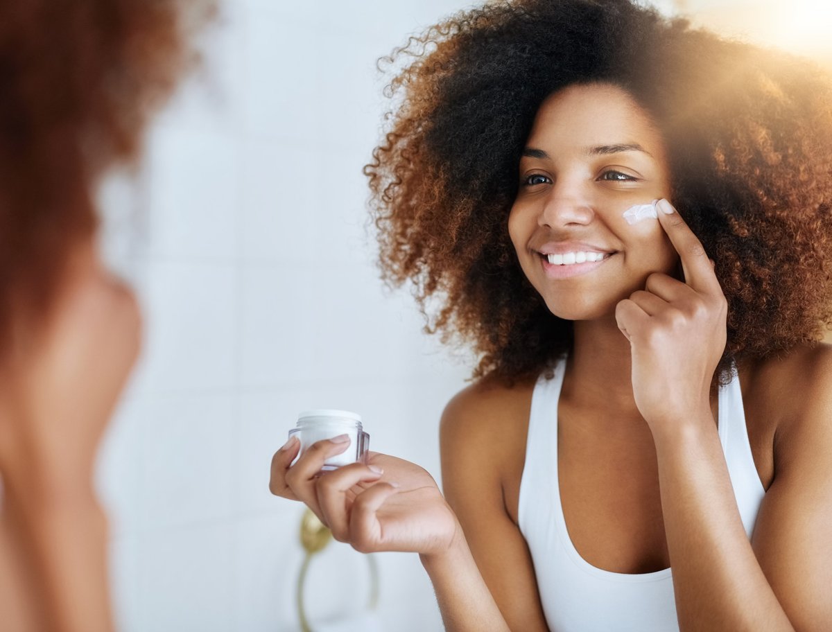 Mujer aplicando crema hidratante sobre piel limpia y natural con luz suave