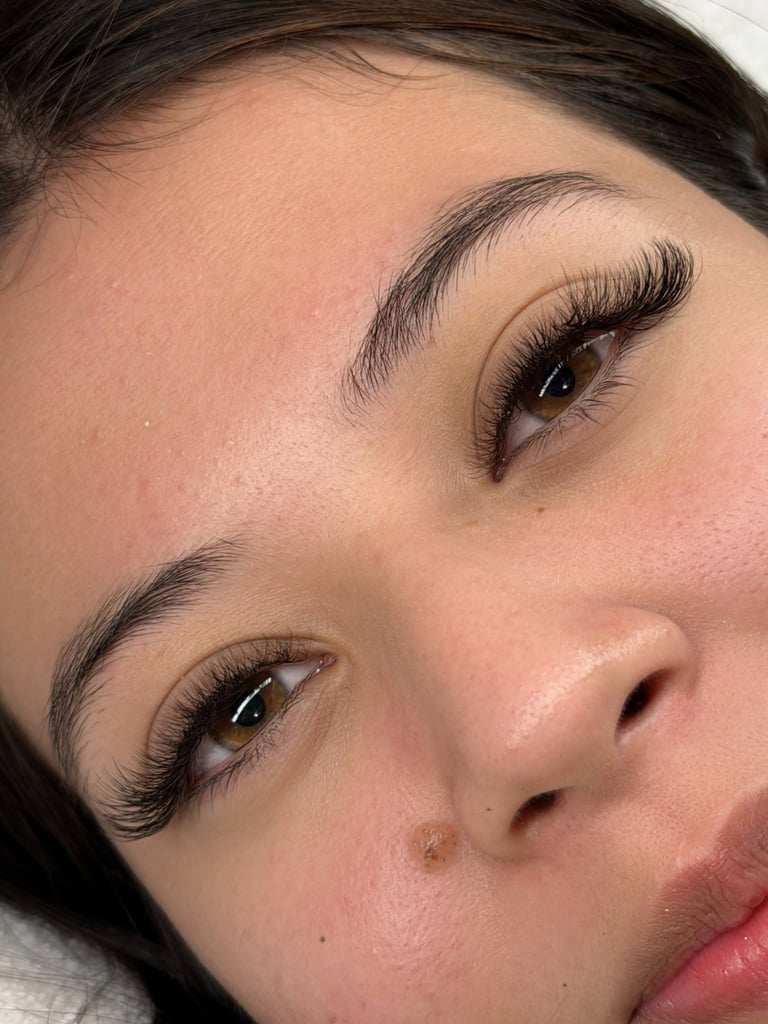 Close-up of a womans face showing voluminous black eyelash extensions and defined eyebrows